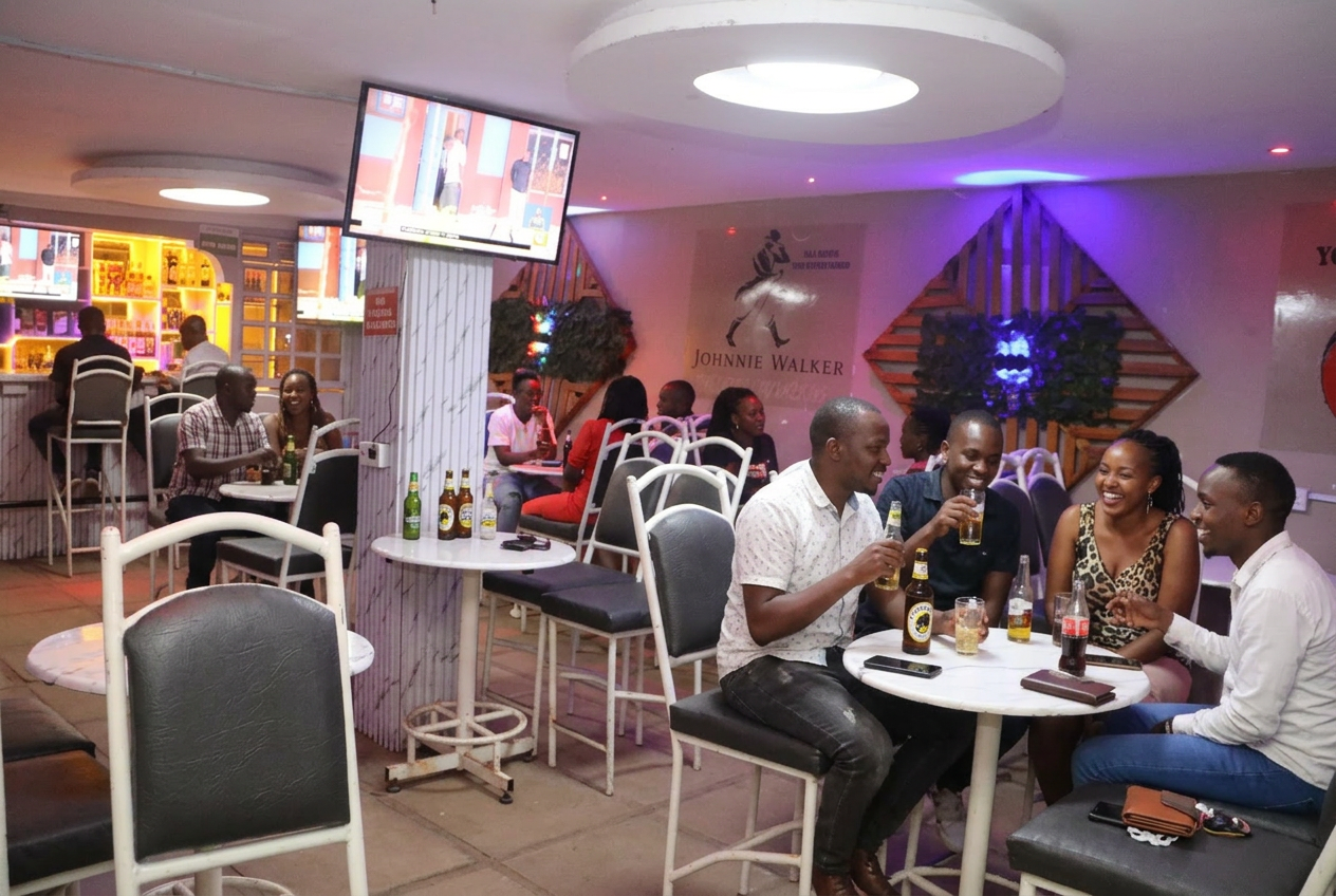 Friends laughing over cold drinks inside T&A Lounge in Kimumu, Eldoret